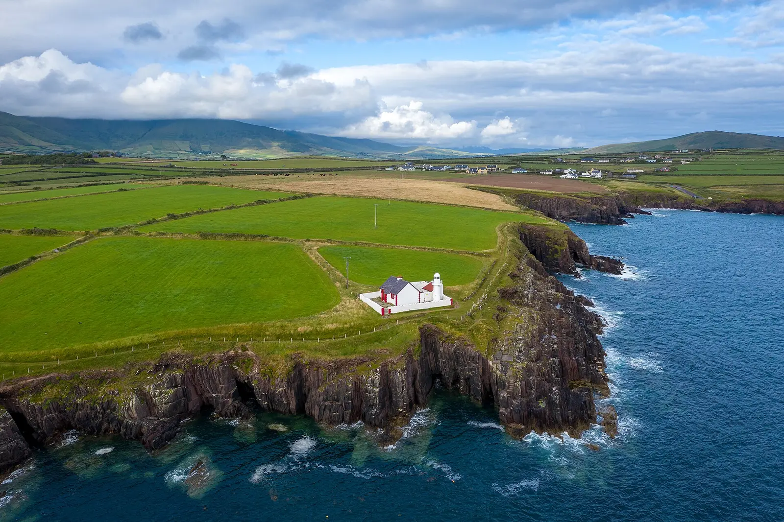 White lighthouse above the blue water outside Dingle Harbour