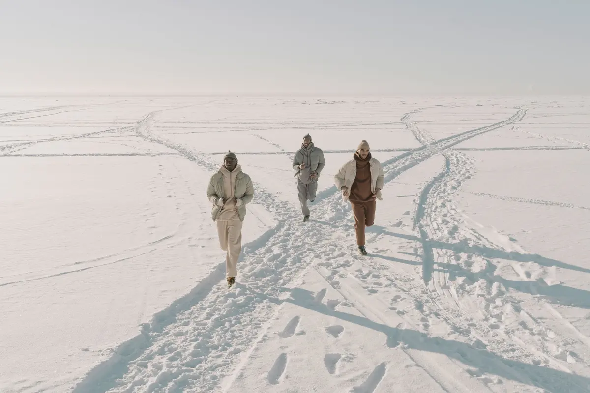A group of men running together through a snow-covered mountain landscape