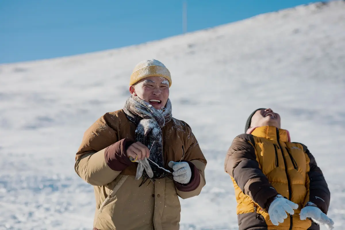 Two men laughing together on a snow-covered mountain slope