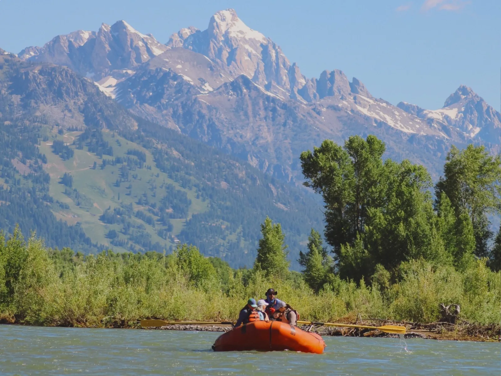 A raft of paddlers floating the Snake River below the Teton range in summer