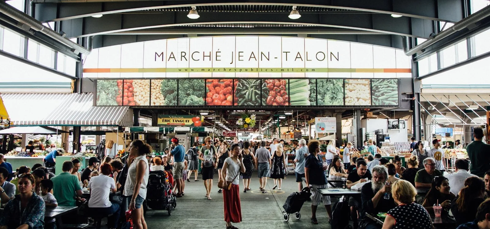 Shoppers under the Marché Jean-Talon sign in the market's open-air hall