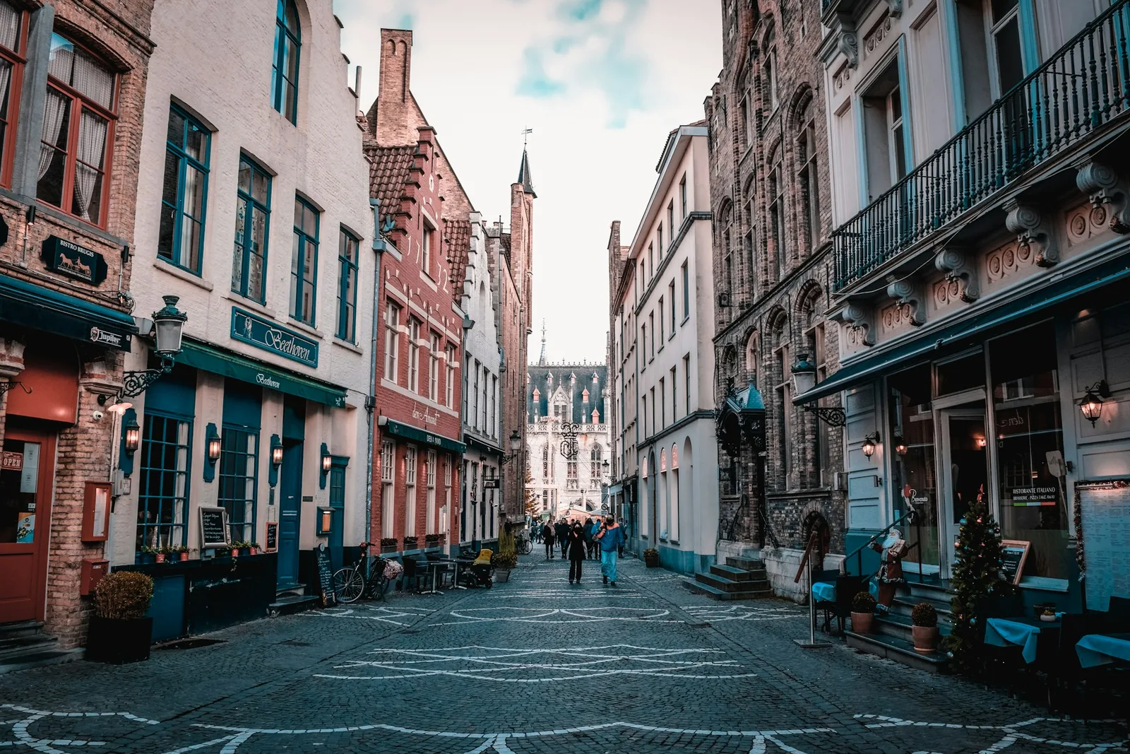 Cobblestone street lined with historic buildings, cafés, and shopfronts in the old city